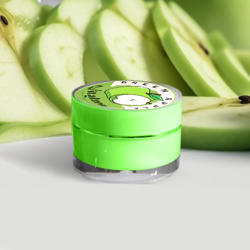 Barattolo di crema labbra Vitalzen al gusto di mela verde, circondato da fette di mela fresca, per labbra morbide e idratate con un tocco di freschezza